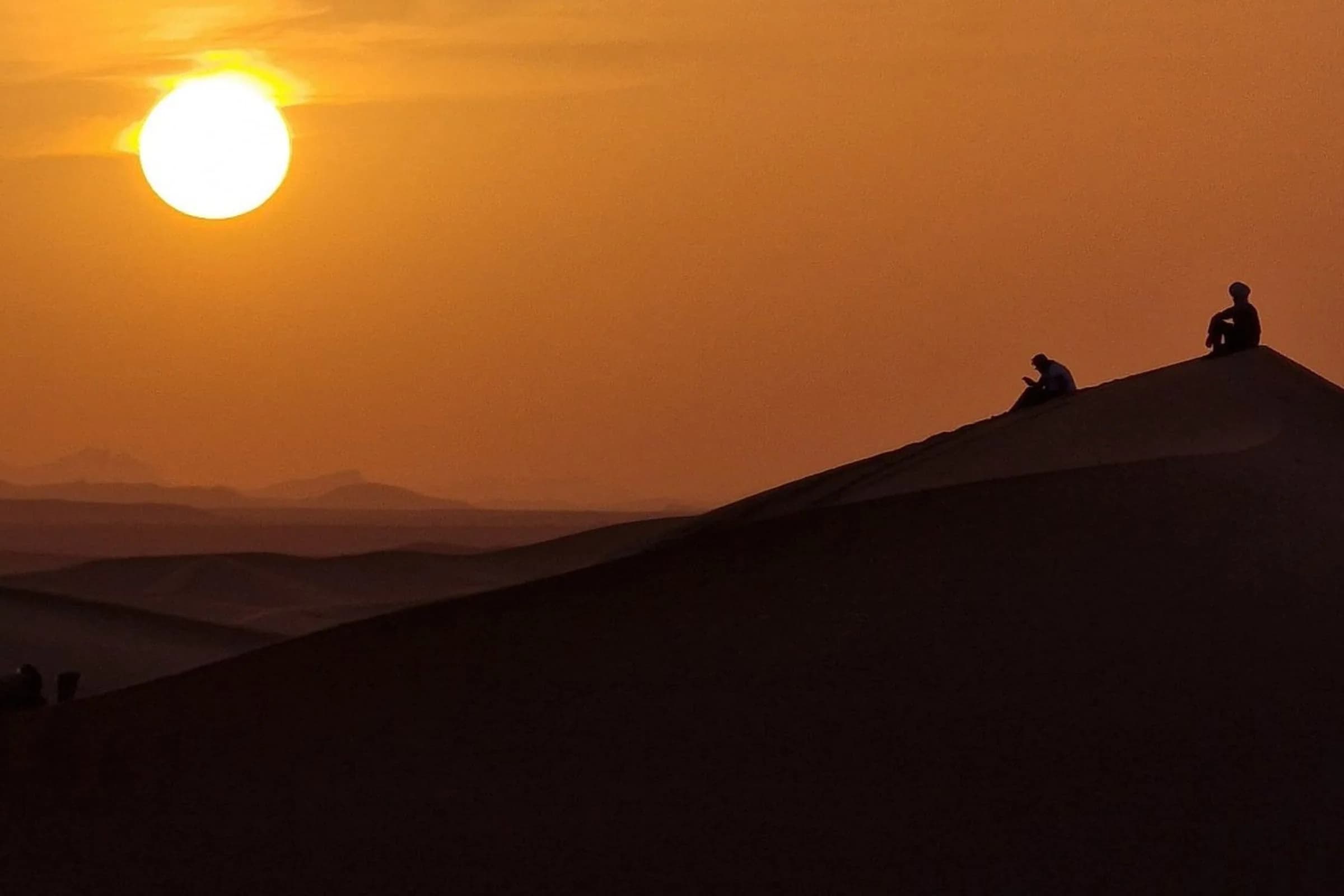 Caravane de dromadaires traversant les dunes de Merzouga au coucher du soleil