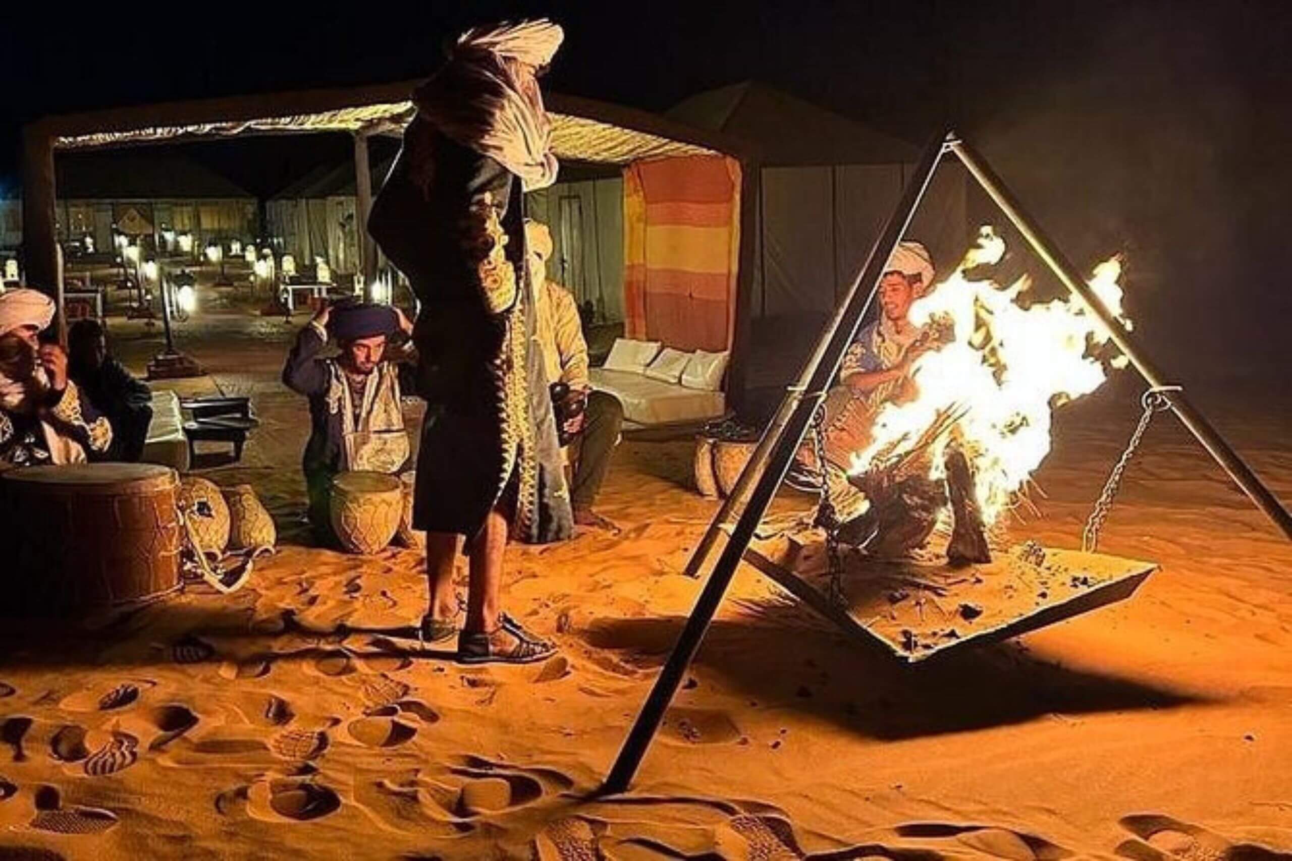 Feu de camp allumé au cœur des dunes lors d’une soirée berbère nocturne à Merzouga