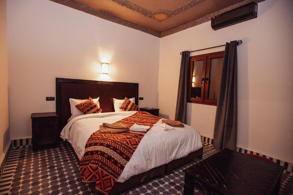 Chambre décorée dans le style berbère d'un riad Merzouga avec textiles colorés, mobilier en bois sculpté et vue sur le désert du Sahara